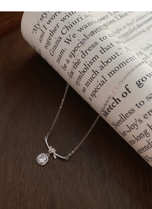 Dettaglio della collana in argento S925 con pendente a cubetto e fiocco su una rivista