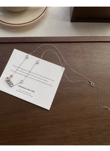 Dettaglio della collana con anello arcobaleno in argento S925 e zirconi su fondo in legno