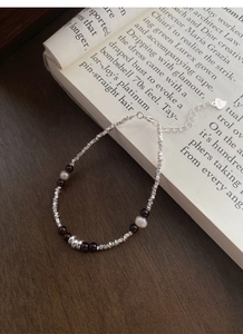 Macro detail of S925 silver bracelet with garnet beads and pearls on vintage book