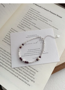 Macro detail of S925 sterling silver bracelet with garnet and pearls on artistic paper