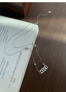 Dettaglio della collana in argento S925 con quattro anelli e zirconi su un libro aperto