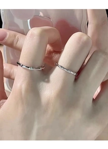 Dettaglio di anelli d'argento stile bambù indossati sulle dita per un look minimalista