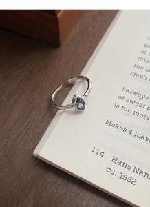 Detailed close-up of sapphire ring with irregular silver texture on book background