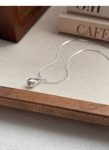 Detail of S925 sterling silver teardrop necklace with star pendant on beige fabric