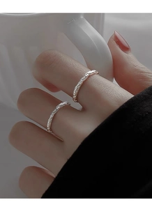 Close-up of minimalist silver rings with hammered texture shown on hand in daily life