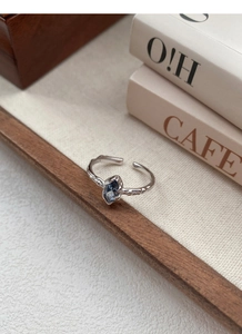 Detailed macro of S925 silver ring featuring irregular texture and blue sapphire marquise stone