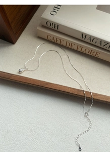 Detail showing S925 sterling silver teardrop pendant with hallmark tag on premium fabric