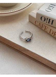 Detailed shot of an irregular texture silver ring featuring a blue zircon oval gemstone