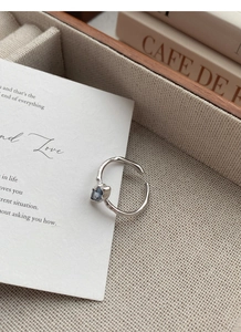 Macro detail of silver open ring featuring irregular texture and blue sapphire gemstone