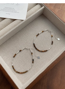 Close-up of S925 silver tiger eye bracelets with heart pendant in a wooden jewelry box