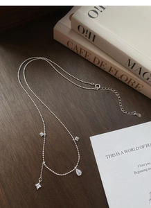 Détail du collier de perles en argent S925 avec pendentifs en zircon sur fond de bois