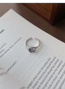 Macro shot of silver ring with irregular texture and blue gemstone on book pages