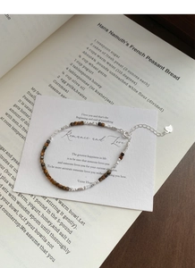 Macro detail of S925 sterling silver tag and natural tiger eye beads on bracelet