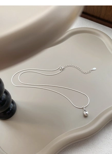 Detailed view of S925 sterling silver waterdrop pendant with fine snake chain on a ceramic tray