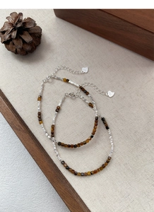 Detailed shot of S925 silver beaded bracelet with natural tiger eye stones on textured fabric