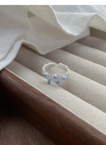 Detail of irregular silver-tone ring with molten texture and five light blue zircons
