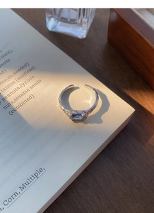 Macro shot of S925 silver ring with lava texture and oval blue zircon on a book
