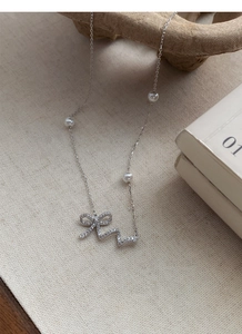 Macro view of 925 silver necklace with sparkling bow pendant and elegant pearls