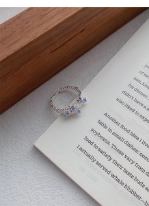 Detail of silver S925 ring with irregular texture and four blue zircon stones