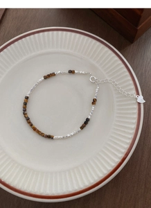 Close-up of S925 sterling silver heart charm and natural brown tiger eye stones on a bracelet