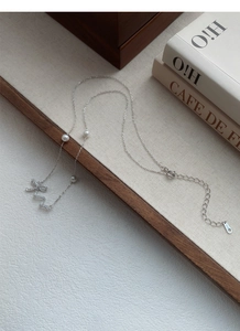 Macro detail of S925 silver bow pendant with diamonds and pearls on a fine chain
