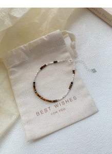 Detailed macro view of S925 sterling silver heart charm and natural tiger eye stone beads