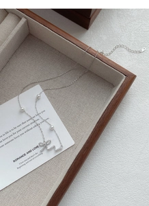 Detail of 925 silver bow necklace featuring pavé crystals and elegant small pearls