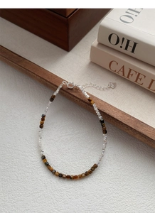 Detail view of tiger eye beads and S925 sterling silver charms on a beaded bracelet