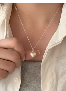 Close-up of a minimalist S925 sterling silver heart necklace with a brushed texture finish
