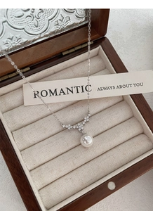 Dettaglio del ciondolo a fiore in argento S925 con diamanti e perla bianca in confezione