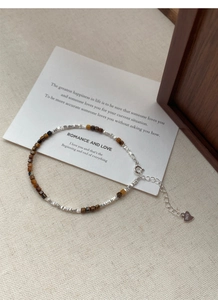 Detail of S925 sterling silver beaded bracelet with tiger eye stones and heart charm