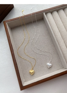 Detail of gold and silver S925 sterling silver heart necklaces with brushed metal finish