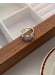 Macro detail of irregular S925 silver ring with blue zircon stones on wood surface