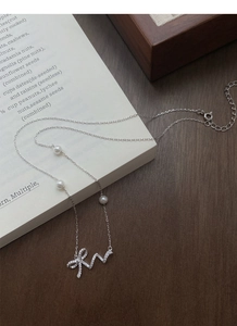 Macro shot of 925 silver bow necklace with micro-set zircons and elegant white pearls