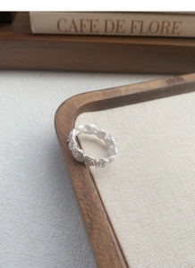 Macro shot of matte S925 sterling silver rose ring displayed on a wooden vintage tray
