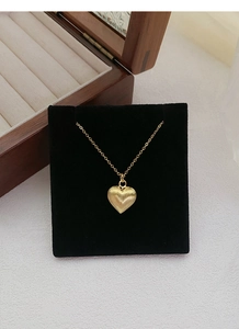 Detailed close-up of S925 silver brushed heart pendant with gold finish on black display