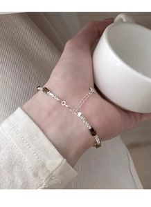 Detailed view of dainty S925 silver bracelet with tiger eye beads on woman's wrist