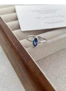 Dettaglio anello in argento S925 con trama martellata e gemma blu a taglio marquise