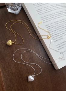 Detailed close-up of S925 sterling silver heart necklaces in gold and silver matte finishes