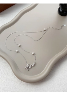 Detailed macro view of S925 silver necklace with bow pendant and white pearls