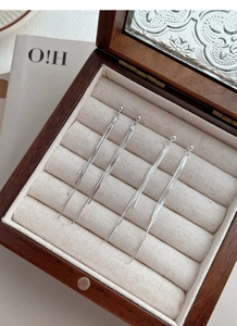 Macro detail of long silver tassel drop earrings displayed in a luxury jewelry box