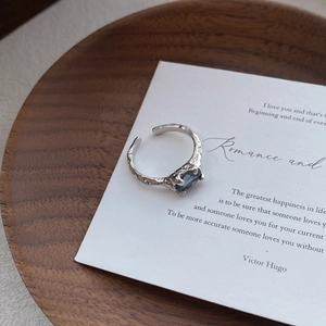 Irregular textured S925 silver ring with oval blue zircon on a white quote card