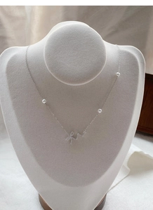 Detail of 925 silver necklace featuring bow pendant with zircons and white pearls
