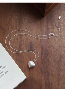 Detail of S925 sterling silver heart pendant with refined brushed matte finish and fine chain