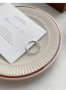 Detailed view of S925 sterling silver beaded ring on elegant porcelain saucer