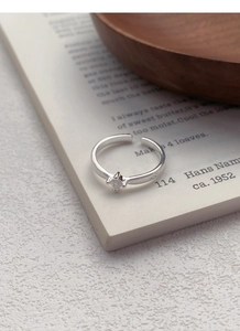 Detailed macro shot of an adjustable silver square diamond ring with vintage texture on a book