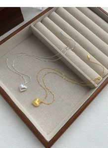 Detail of S925 sterling silver heart necklaces with brushed texture in gold and silver