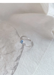 Dettaglio anello in argento S925 con trama liquida irregolare e zircone blu tondo