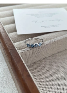 Dettaglio macro dell'anello in argento S925 con texture irregolare e quattro zirconi blu