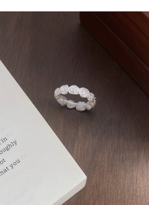 Detailed close-up of matte silver vintage rose floral patterns on a wide ring band